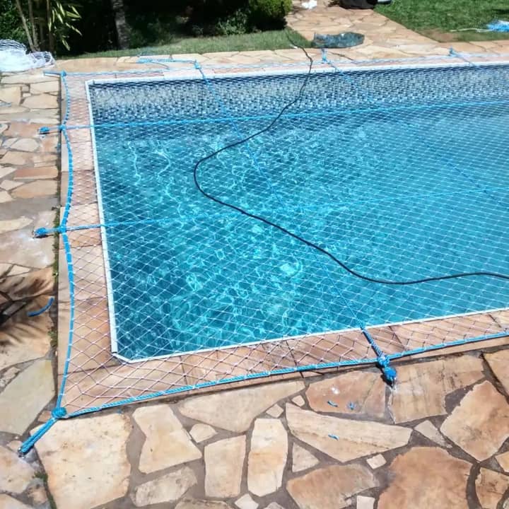 Piscina com borda de pedra e rede de proteção