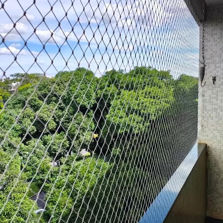 Rede de proteção branca de perto em varanda com vista para árvores